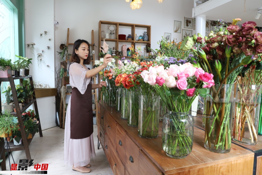 王黎媛是一名河南姑娘，在昆明念完大學后，就再也舍不下春城的藍天陽光、青山碧水，更舍不下這里的四時繁花，于是就干脆留了下來，成了一名媒體人。2017年的時候又毅然辭去工作，創(chuàng)業(yè)開起了花店，成了都市里的一名“花房姑娘”。圖為王黎媛在自己的花店中整理鮮花。新華網(wǎng) 周亞平/攝 念新洪/文